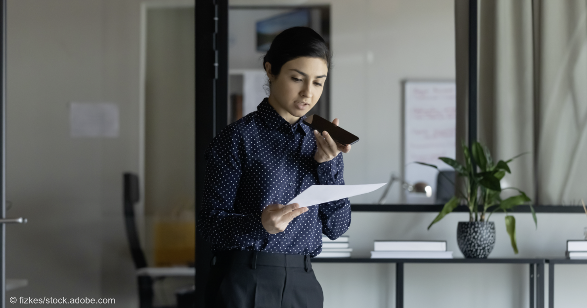 Eine Frau in einem Büro spricht in ein Diktiergerät