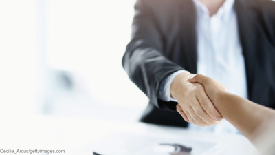 Zwei Personen im Anzug schütteln sich die Hände