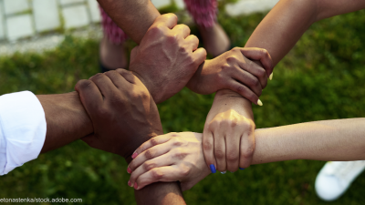 Eine Nahaufnahme von fünf Händen, die sich gegenseitig festhalten