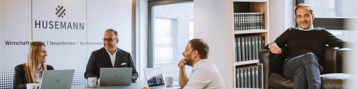 Links sitzt ein Team von Rechtsanwälten und bespricht gemeinsam Mandate im modernen Besprechungsraum einer Wirtschaftskanzlei, mit Laptops und Unterlagen am Tisch. Rechts sitzt ein Partner der Kanzlei im Büro mit Bücherregal im Hintergrund.