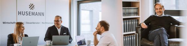 Links sitzt ein Team von Rechtsanwälten und bespricht gemeinsam Mandate im modernen Besprechungsraum einer Wirtschaftskanzlei, mit Laptops und Unterlagen am Tisch. Rechts sitzt ein Partner der Kanzlei im Büro mit Bücherregal im Hintergrund.